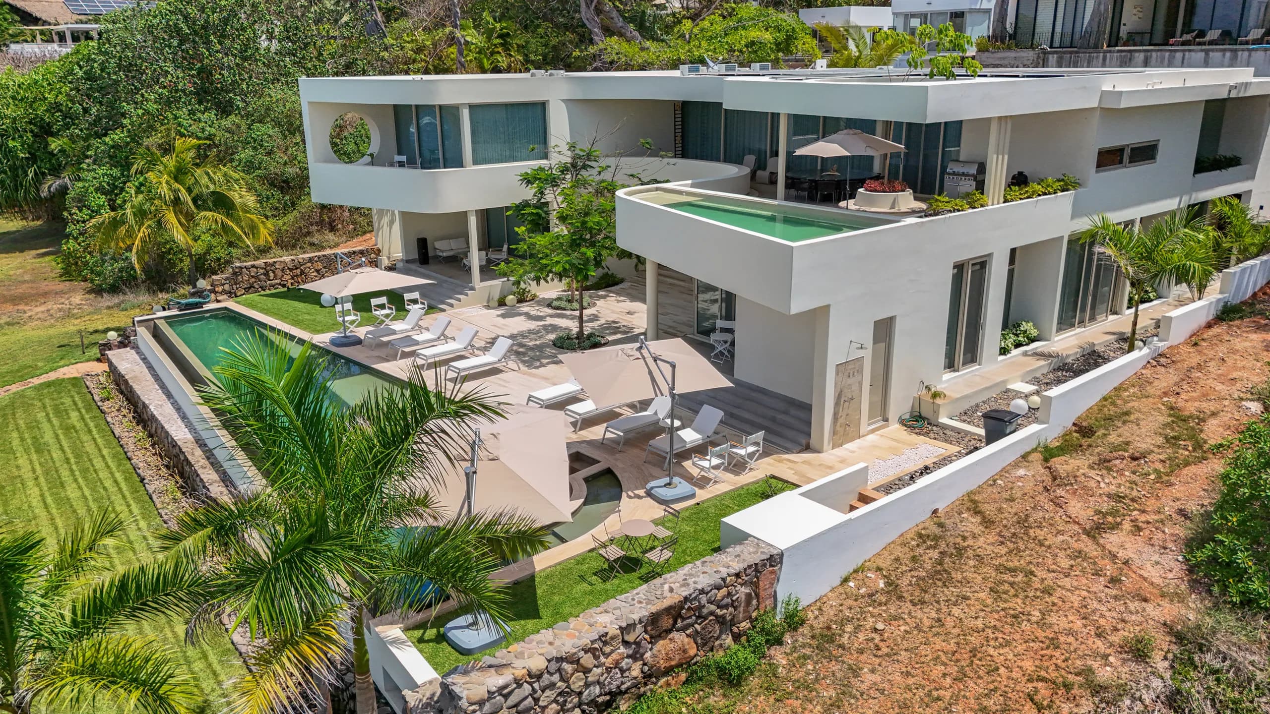 Una perspectiva arquitectónica elevada que resalta las terrazas, espacios exteriores y la privilegiada ubicación frente al mar.