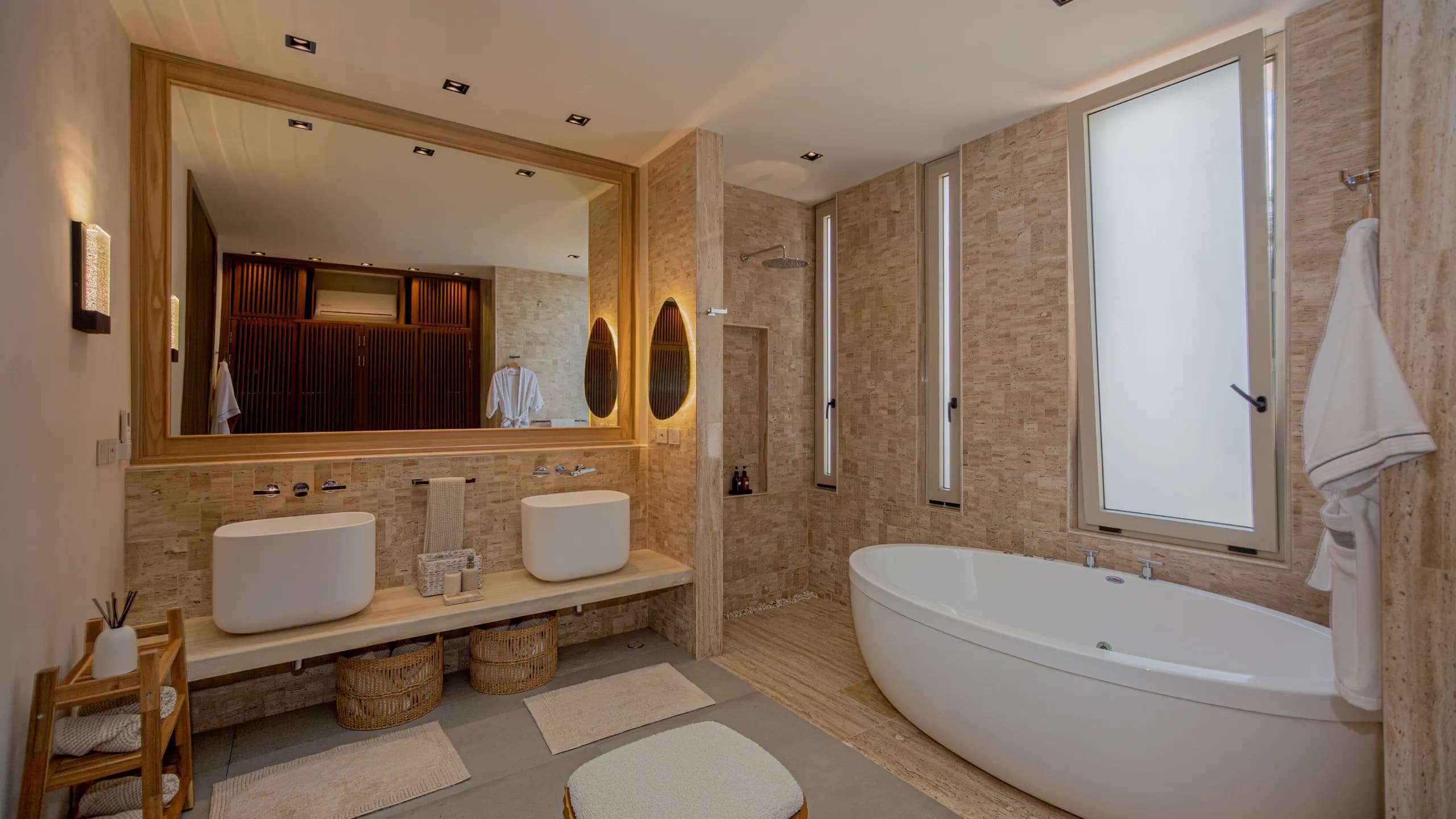 Baño principal inspirado en un ambiente tipo spa, con texturas naturales, iluminación cálida y acabados contemporáneos.