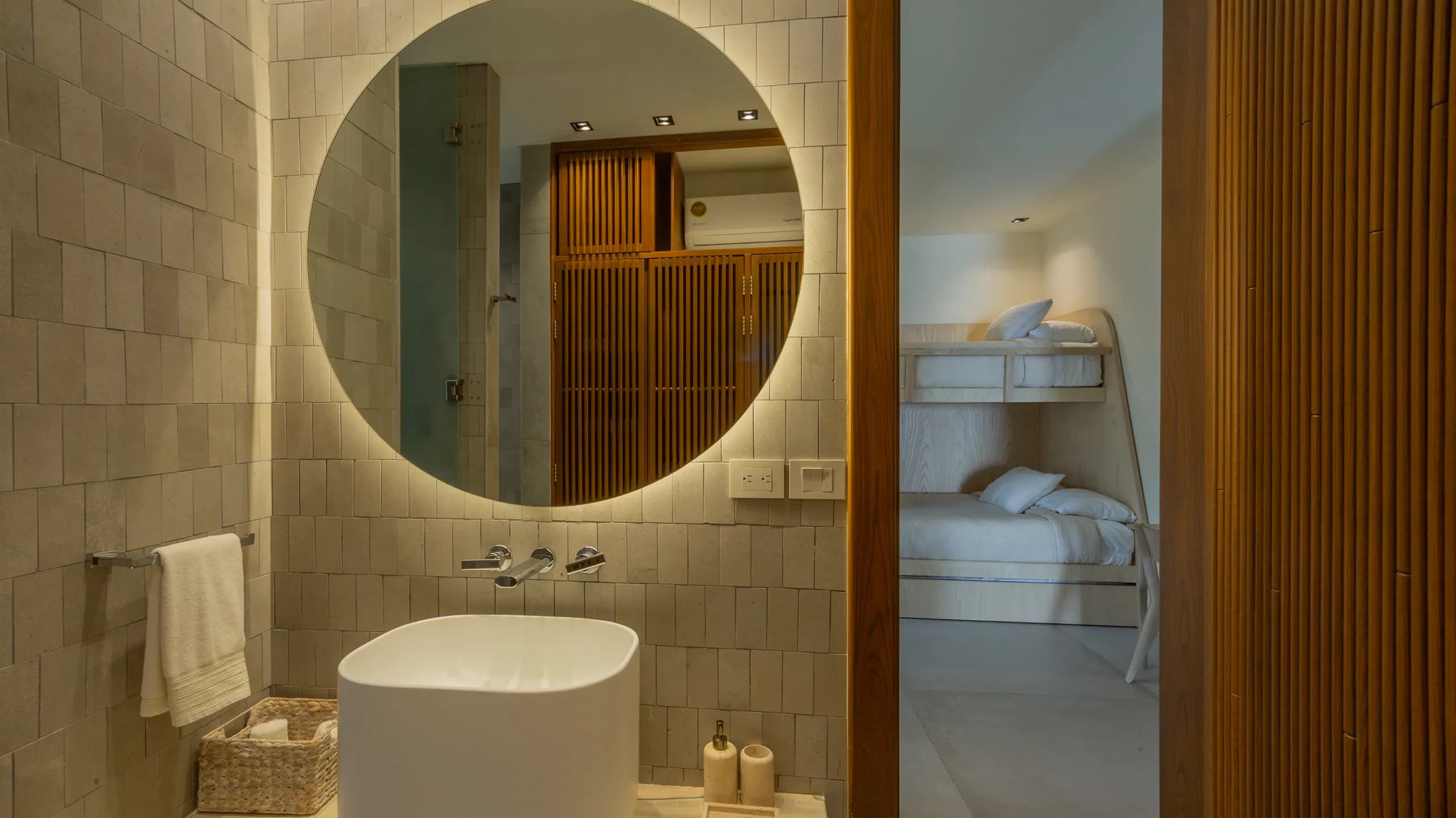 Detalles de baño que integran acabados en madera, texturas naturales e iluminación arquitectónica sutil.