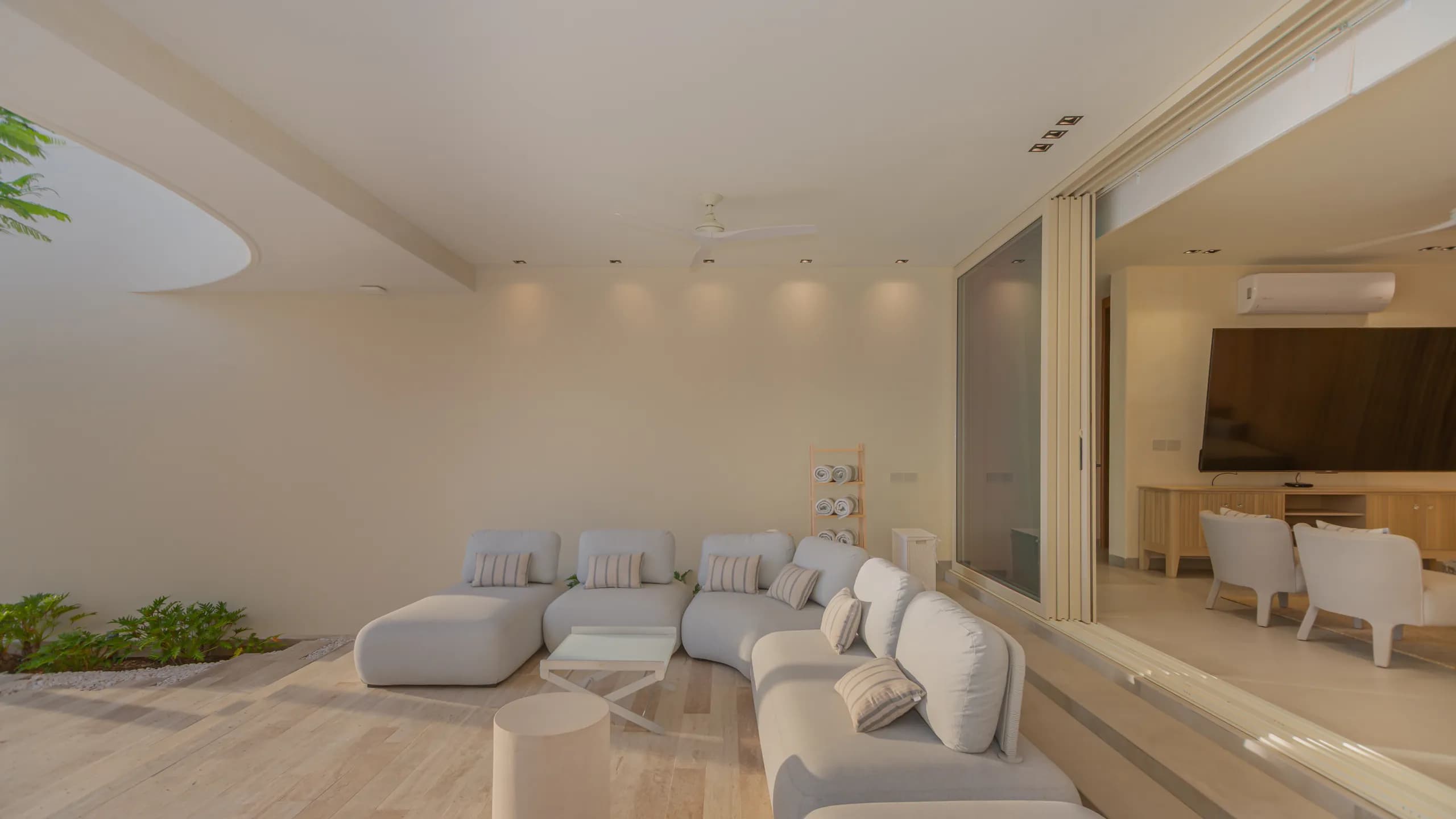 Área lounge exterior techada integrada naturalmente con los espacios interiores, diseñada para disfrutar del entorno frente al mar durante todo el año.