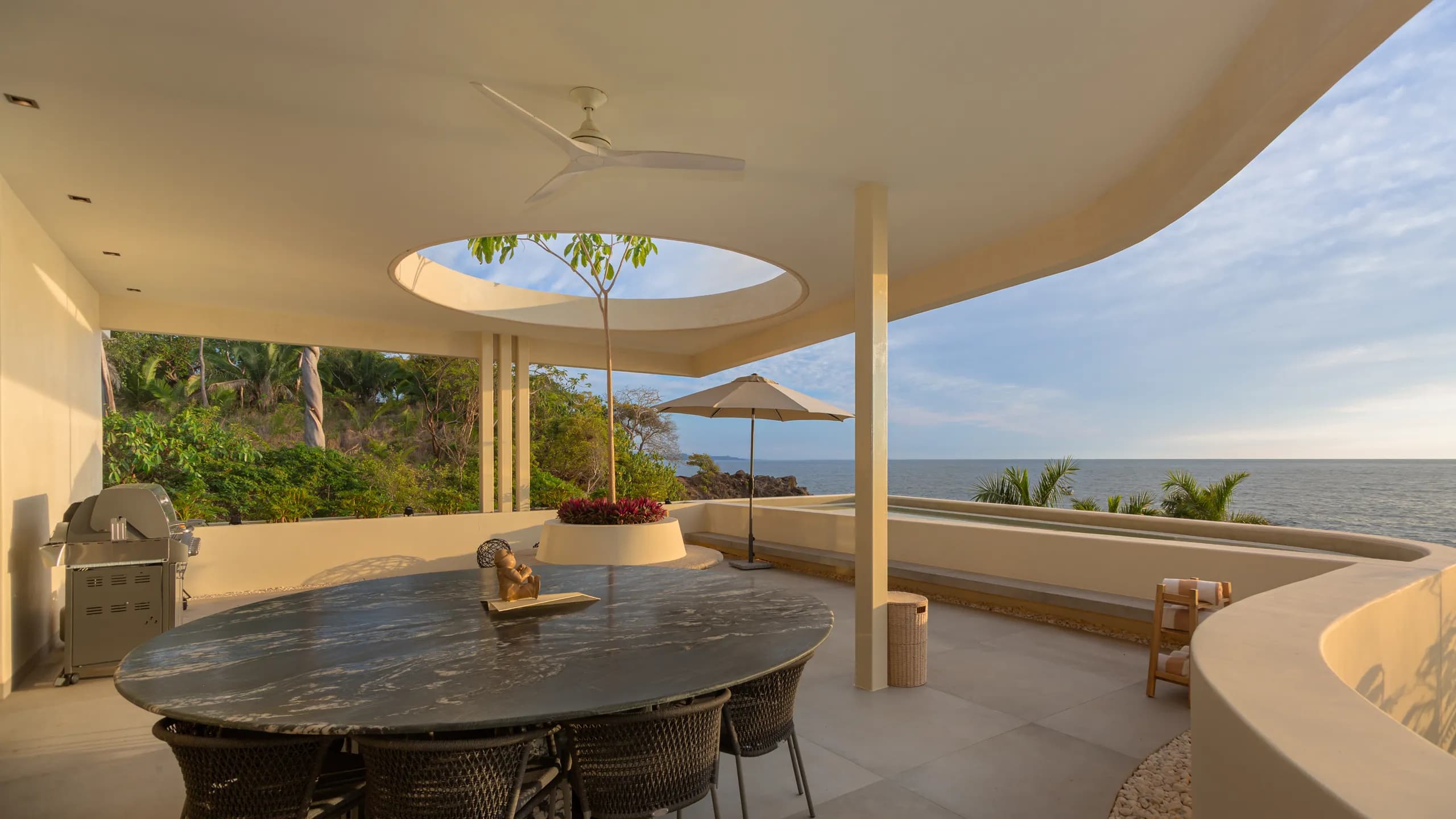 Terraza privada para comedor exterior con vista al Pacífico, enmarcada por líneas arquitectónicas esculturales y vistas abiertas al mar.