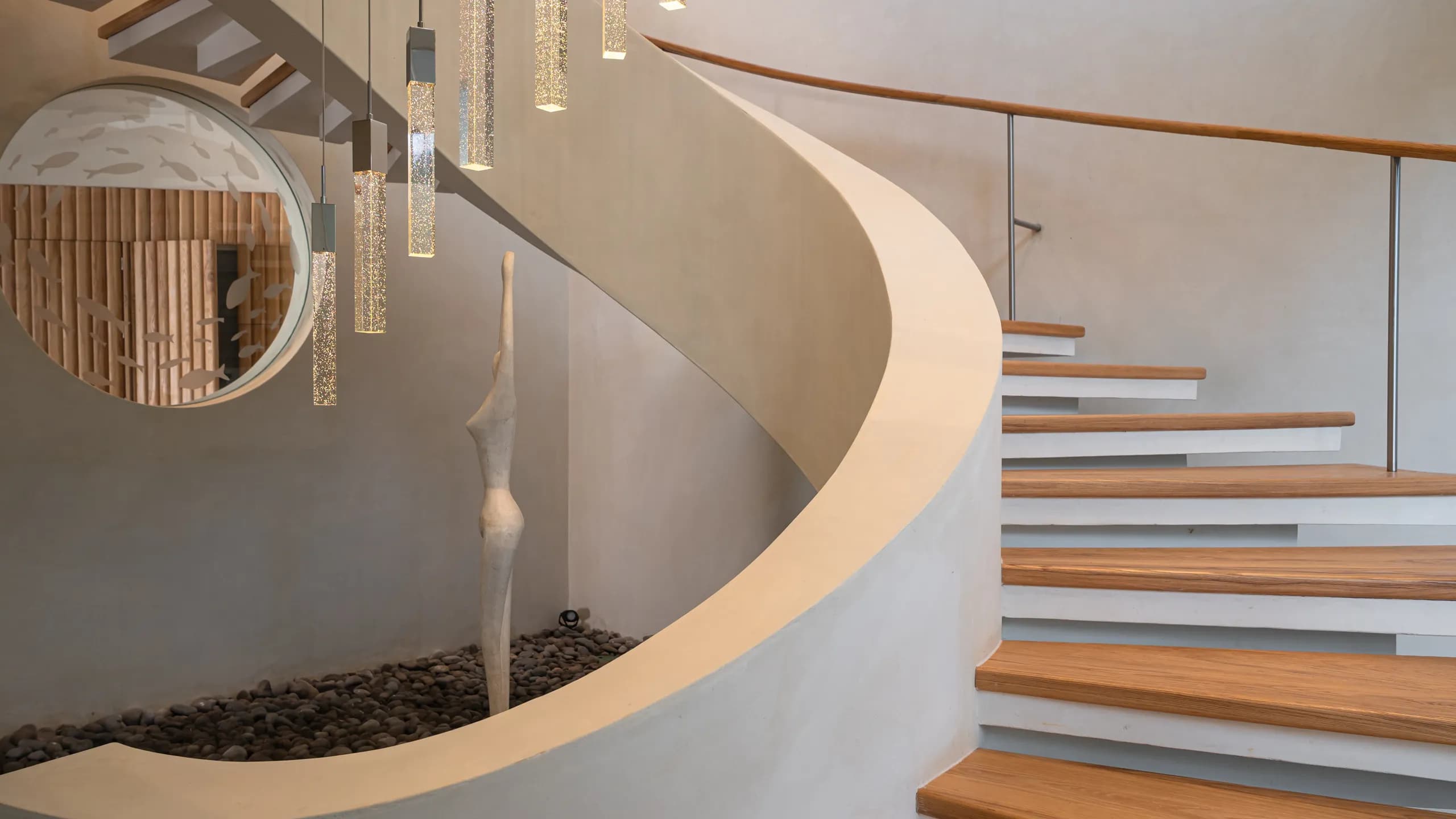 La escalera escultórica funciona como una pieza arquitectónica central que combina diseño contemporáneo, formas orgánicas y materiales cálidos.