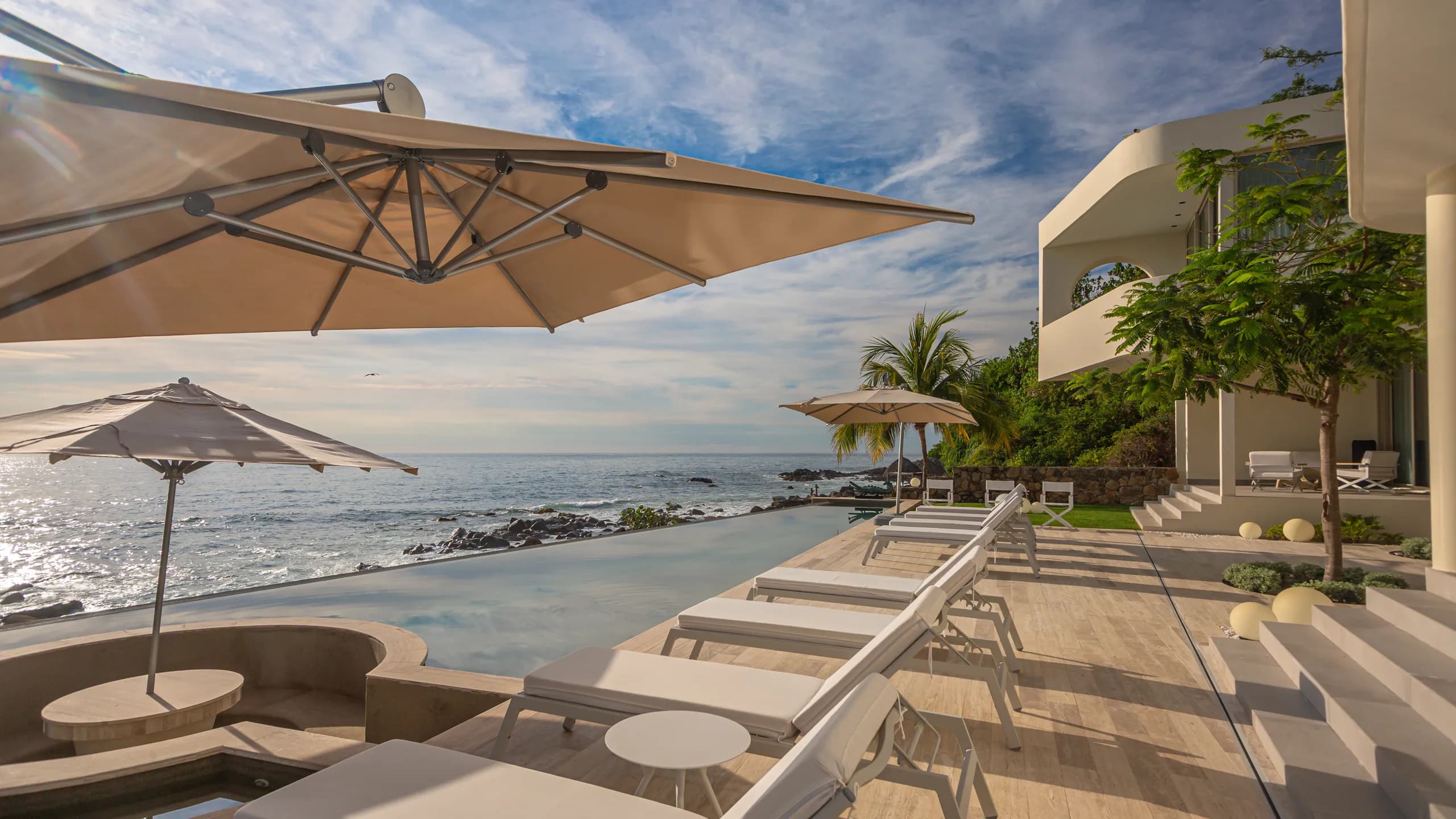 Espacios lounge frente al mar cuidadosamente integrados al entorno costero para una experiencia residencial abierta y sofisticada.